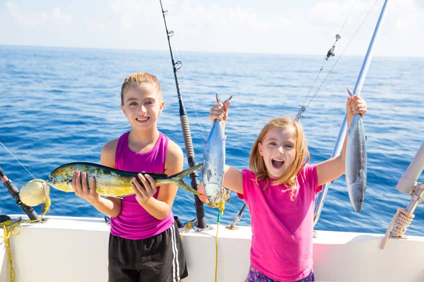 Happy children holding up their catch of fish from deep sea fishing.