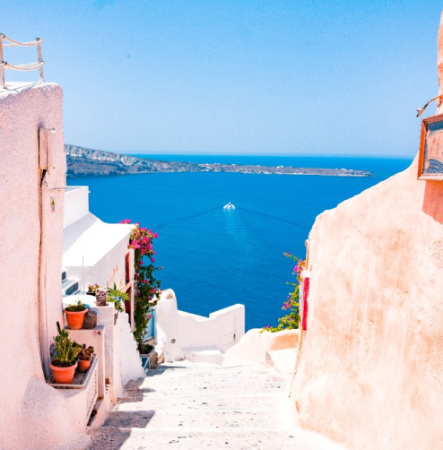 a view of the ocean from a small street high on a hill